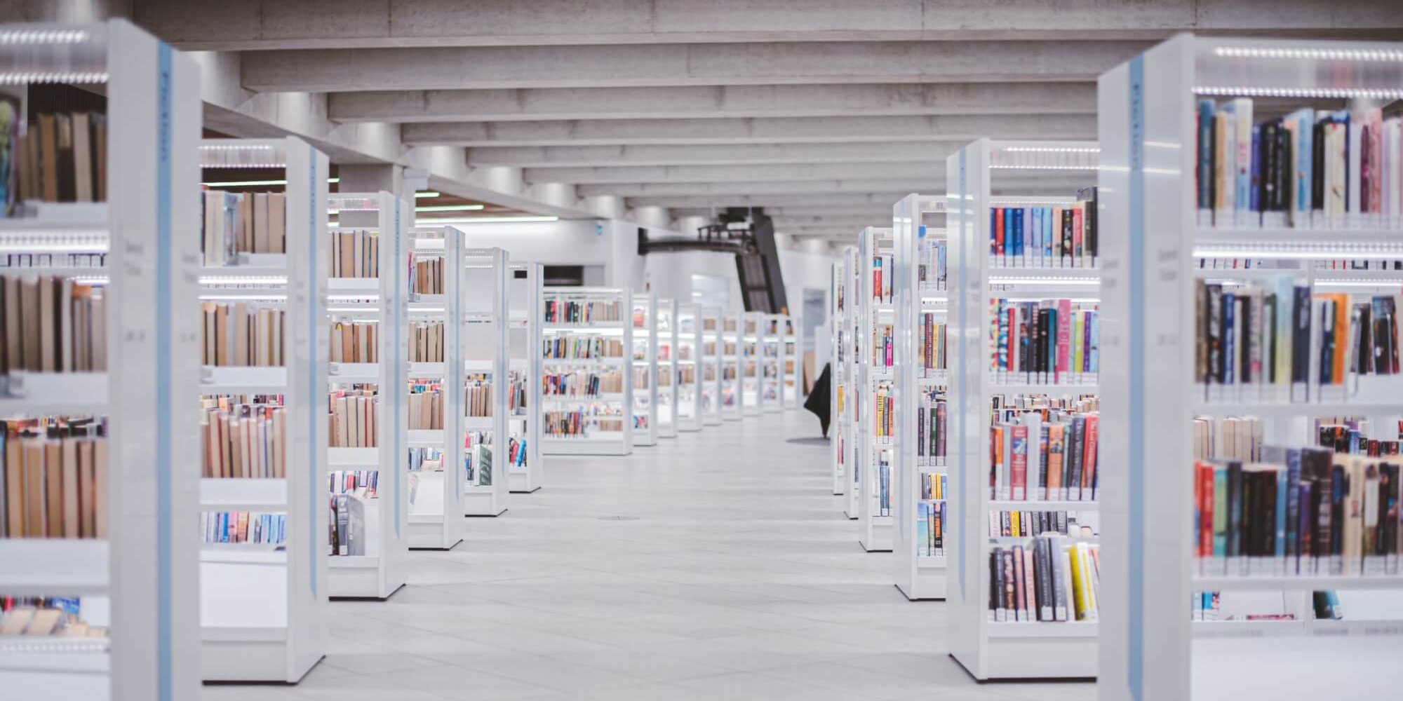 Ansicht eines Ganges in einer Bibliothek mit verschiedenen Regalen voller Bücher.